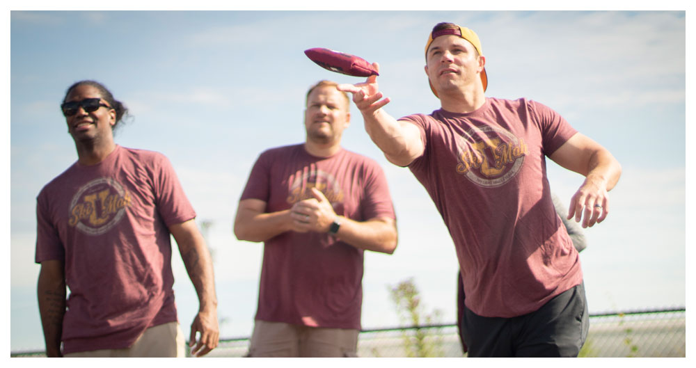 Maroon shirt bean bag toss promotional shot